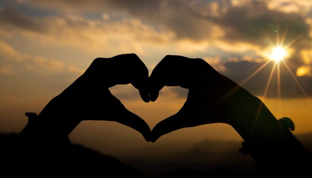 Heart shape from two hand with sunrise background.