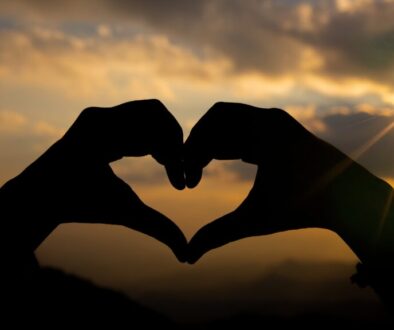 Heart shape from two hand with sunrise background.